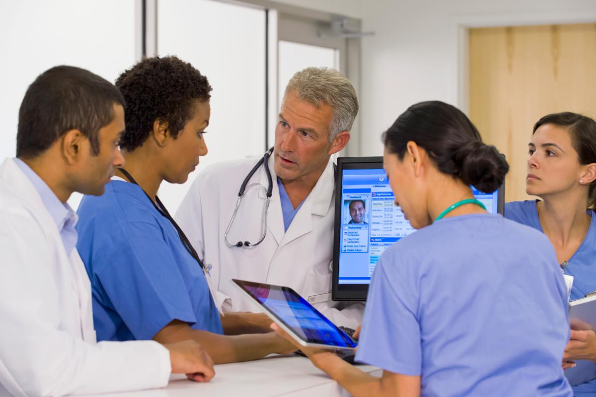 Physician consultation around laptop and tablet.